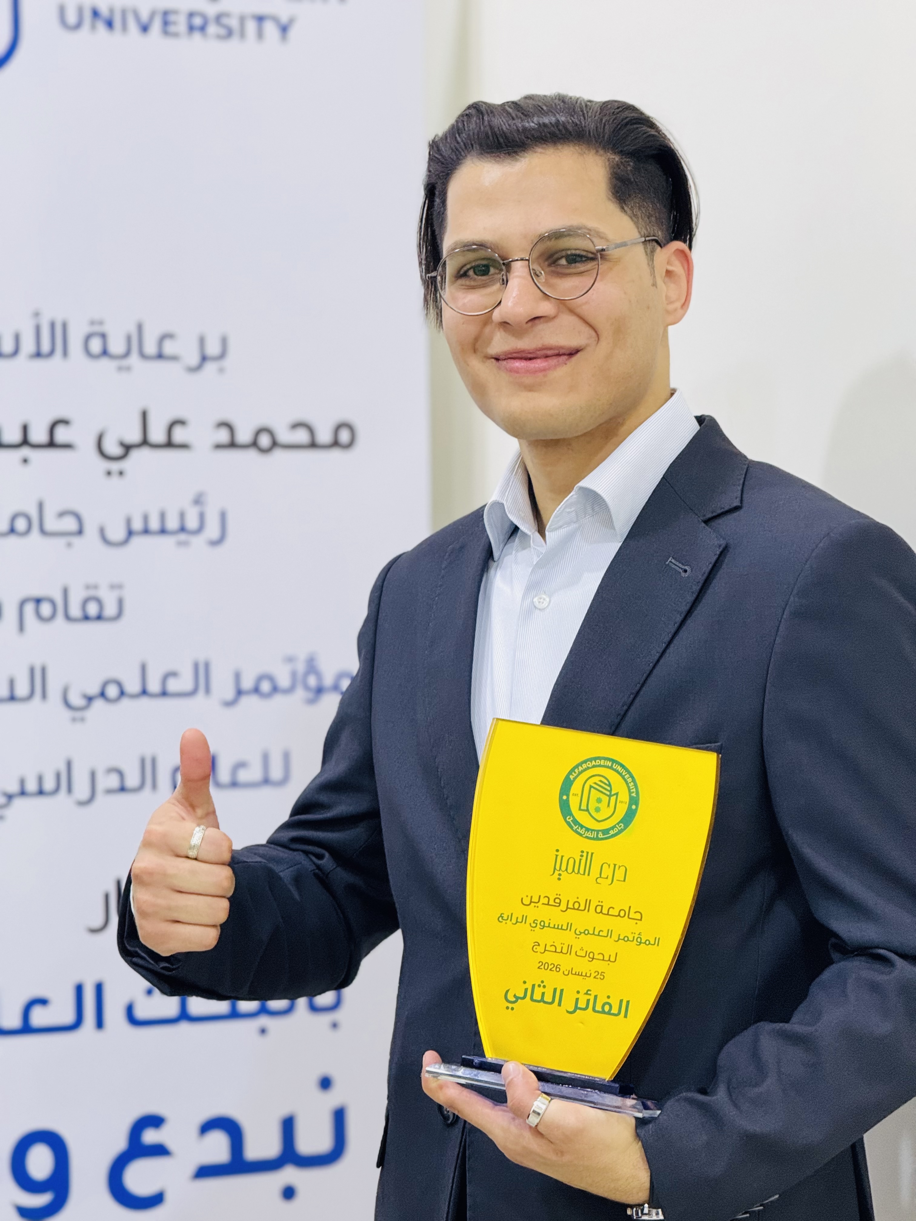 Ahmad Faiq holding the second-place graduation research trophy